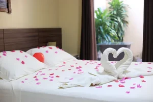 Cama de casal com decoração romântica (cisnes de toalha, pétalas) no quarto duplo da Pousada Bellíssima Itália, Luis Correia.