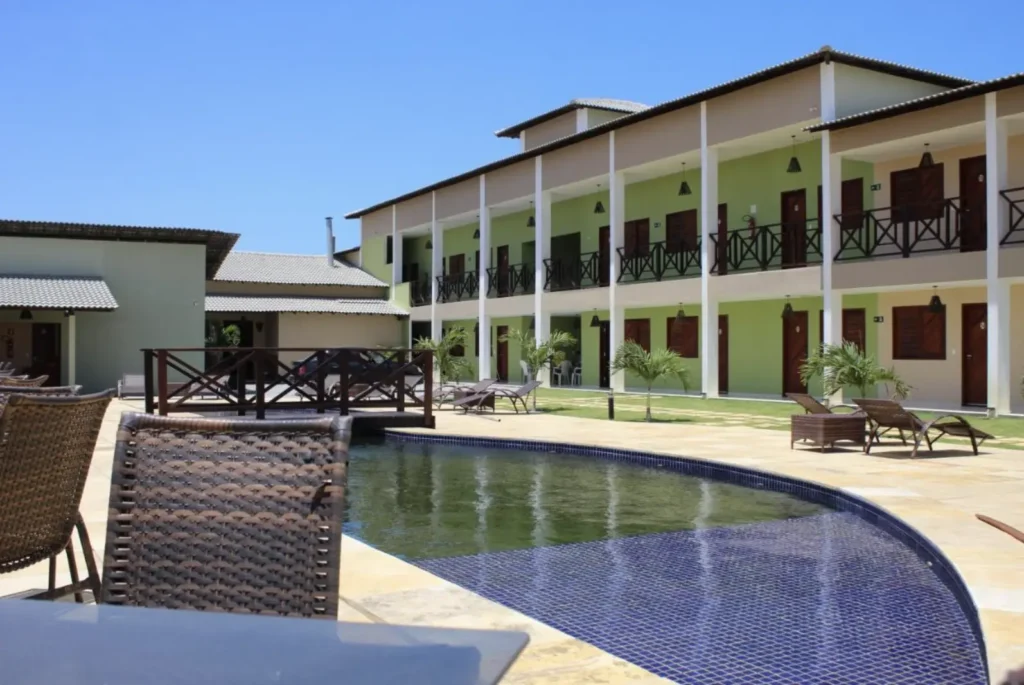 Vista da Piscina e Acomodações - Pousada Bellíssima Itália Piscina da Pousada Bellíssima Itália em Luis Correia, com área de lazer e vista para o prédio dos apartamentos com varanda. Quartos confortáveis para família