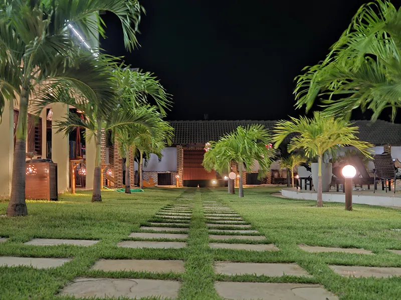 Jardim e Paisagismo Noturno - Pousada Bellíssima Itália Jardim com paisagismo e iluminação noturna na Jardim com paisagismo e iluminação noturna na Pousada Bellíssima Itália em Luis Correia, com caminho e palmeiras.