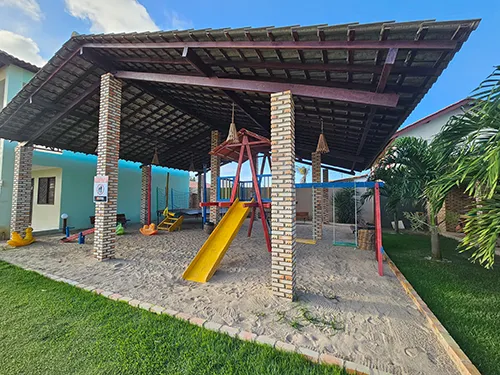 Parquinho Infantil - Lazer para Famílias na Bellíssima Itália Parque infantil (parquinho) coberto da Pousada Bellíssima Itália em Luis Correia, vista diurna com brinquedos e área de areia.
