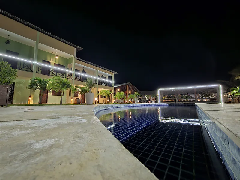 Piscina Iluminada à Noite - Pousada Bellíssima Itália Vista noturna da piscina iluminada e área de lazer da Pousada Bellíssima Itália em Luis Correia.